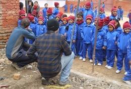 Nepal Local children in Nepal look on excitedly while volunteers help with building classrooms for a school damaged during the 2015 earthquake.