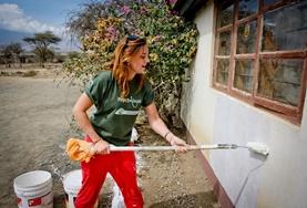 Building A Building volunteer paints the wall of a completed school building at her placement in Tanzania.