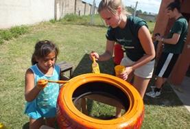 Argentina A childcare volunteer and a local child work together to paint a tyre to be repurposed for a playground in Argentina.