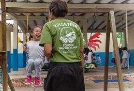 Ecuador A childcare volunteer pushes a young girl on a swing in a playground in Ecuador.