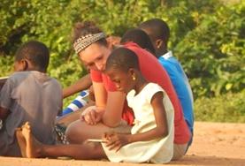 Ghana A Care volunteer reads a book with a young student in Ghana.