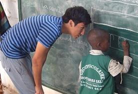 Senegal A childcare volunteer teaches a local child in Senegal how to write using a blackboard.