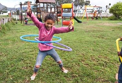 South Africa A young child plays with hula hoops on a playground at our volunteer childcare placement in Cape Town, South Africa.