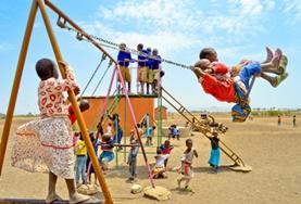 Tanzania School children swinging together on a playground at our volunteer childcare placement in Tanzania.