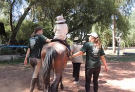 Bolivia Two Equine Therapy volunteers support a child during a treatment session at our Care placement in Bolivia.