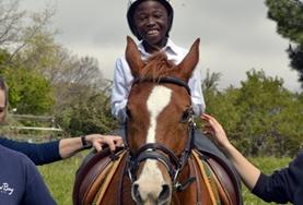 South Africa A volunteer supports a disabled boy as he rides his therapy horse at our Equine Therapy placement in South Africa.