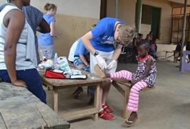 Medicine A Medicine volunteer in Ghana assists with cleaning a child's wound during a healthcare outreach over the Christmas period.