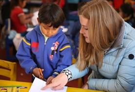 Peru A childcare volunteer guides a child through his homework at our Care & Community placement in Peru.