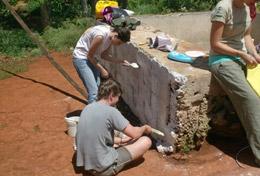 Jamaica High School Project Building volunteers cover a brick wall with cement in a local community in Jamaica.