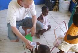 Jamaica A Care & Community volunteer gives a fresh glass of water to a young child at a childcare centre in Jamaica.