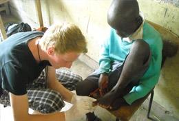 Kenya A high school student volunteering in Kenya helps with disinfecting a child's wound at a Medicine community outreach.