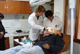 Peru A Dentistry volunteer assists while a dentist examines a patient's teeth at a hospital in Peru.