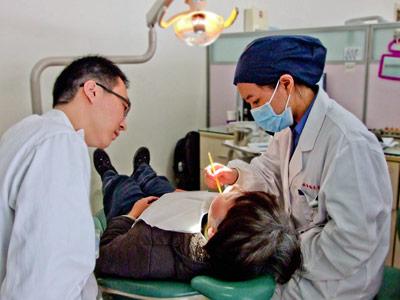 Volunteer treats patient at Dentistry project in China Projects Abroad Dentistry volunteer assesses a young boy at her placement in China
