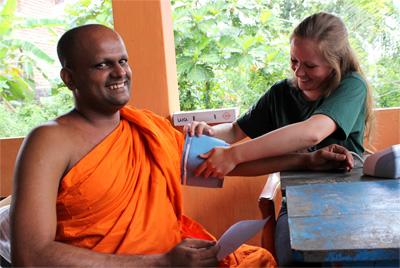 Medical volunteer tests blood sugar and blood pressure at outreach project Projects Abroad Medicine volunteers test blood sugar and blood pressure at Medical outreach camp in rural Colombo