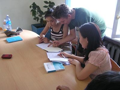 A volunteer assists his student with her homework at a school in Mongolia. A volunteer helps his student with her homework in a classroom in Mongolia, Asia.